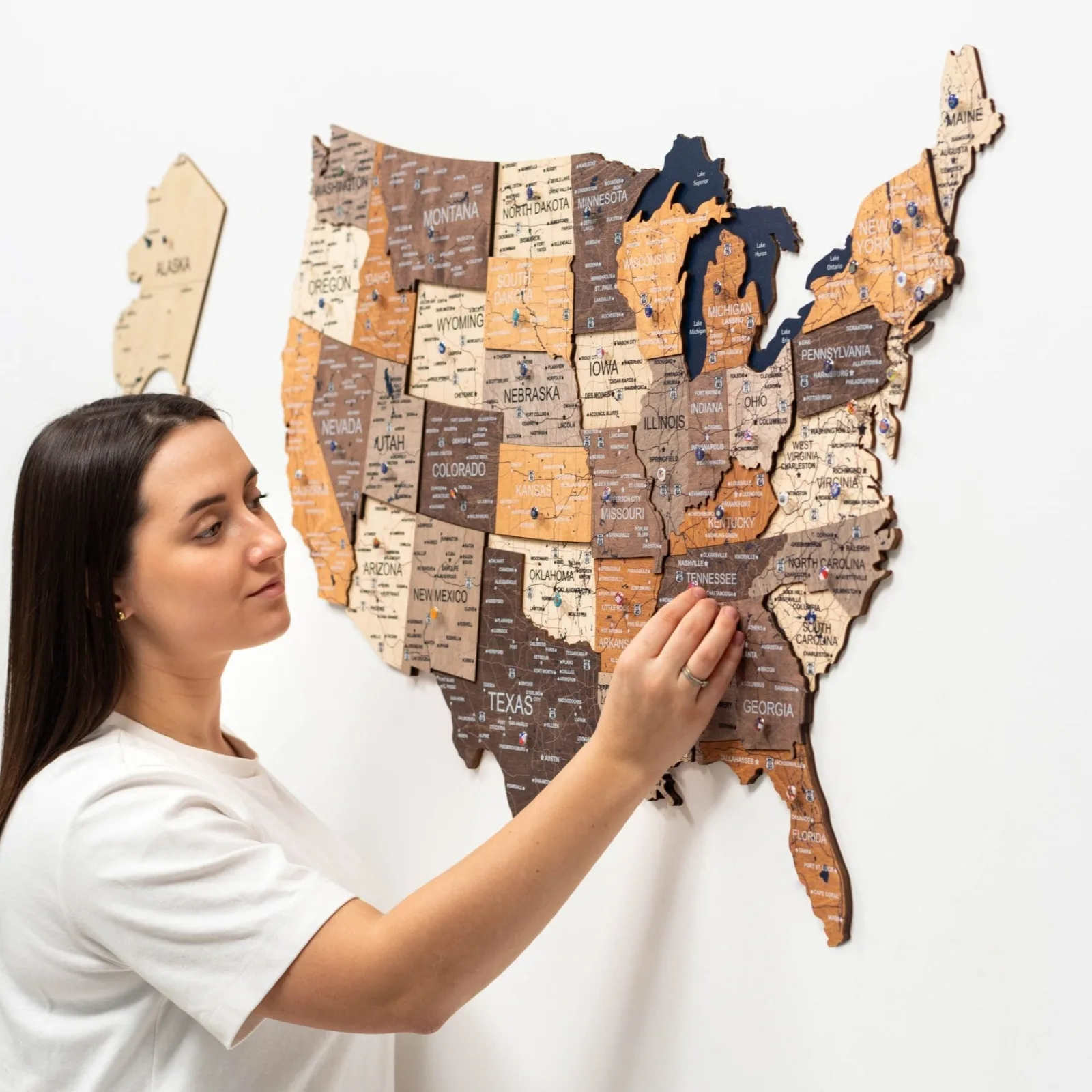 Woman touching a multicolor 3D wooden USA map on a white wall